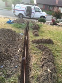 Open trench with a new sewer line installed in a front yard